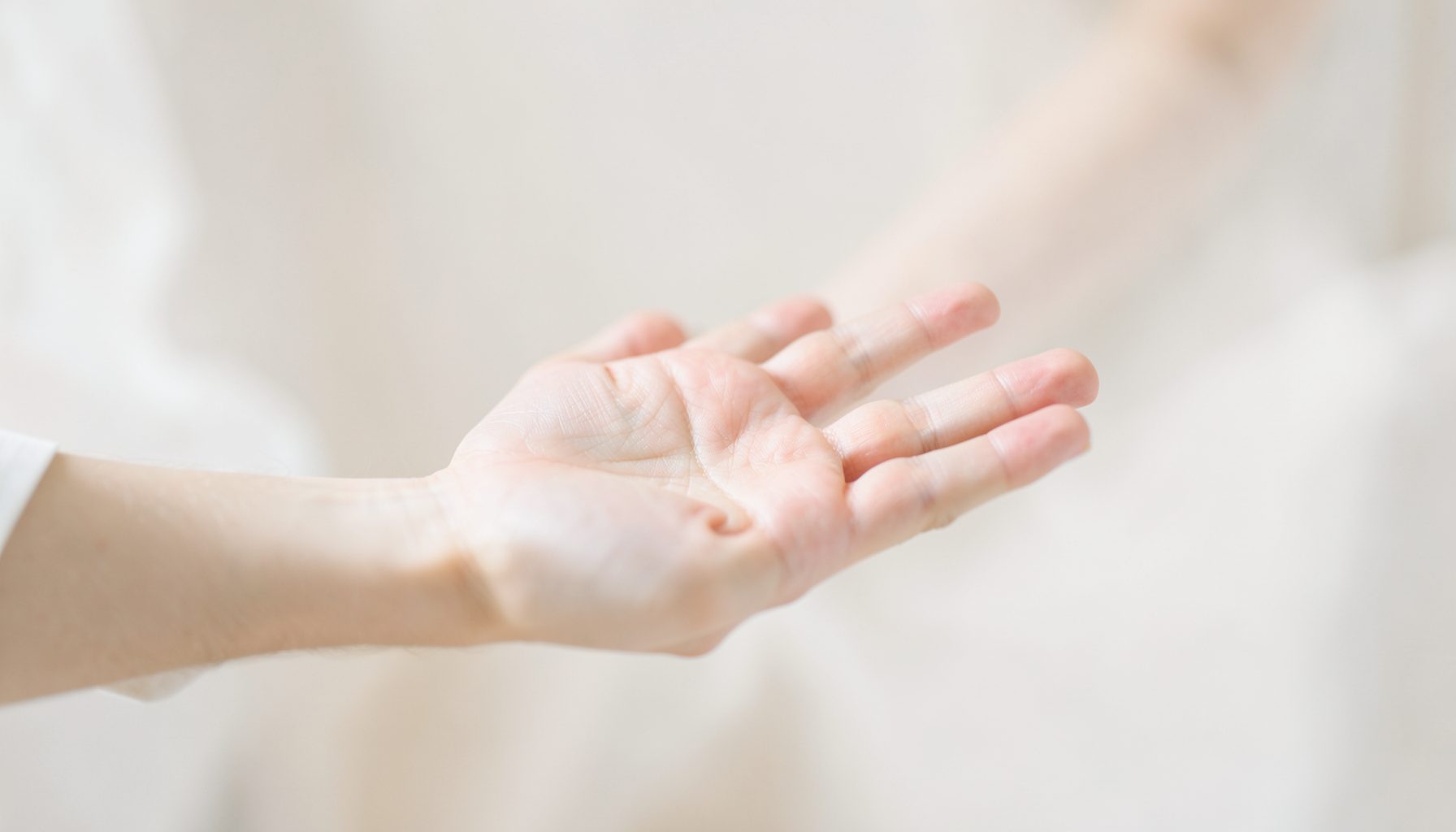Bàn tay mở rộng dưới ánh sáng mềm mại, tông màu be và trắng thanh bình